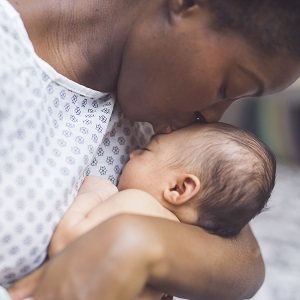 Woman kissing her newborn infant on the forehead