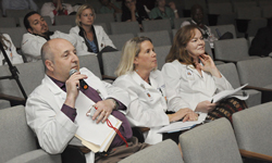 Image: Michael Lewis, MD, addresses a Sim Wars team during the April 8 competition. Linda Edwards, MD, and Cynthia Leaphart, MD, look on. The three served as the Sim Wars judges.