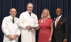 Image: Toward the end of the program, UF COMJ leaders recognized George “Skip” Wilson III, MD (second from left), who’s retiring at the end of the month. The longtime faculty member has most recently served as senior associate dean for clinical affairs.