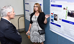 Image: Emergency medicine resident Alexandra Mannix, MD, discusses her poster display for Advances in Medical Education, which proceeded the graduation ceremony. Jeffrey House, DO, an associate professor of medicine and director of the internal medicine residency program, looks on.