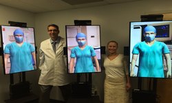 Image: Scott Lind, MD, and Whitney Goering, MD, alongside the three virtual humans used to train residents on operating room protocol.