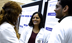 Image: Internal medicine resident physicians, from left, Trisha Shelley, DO; Ashley Thomas, MD; and Satish Maharaj, MD, converse while viewing some of the posters on display during Celebration of Research.