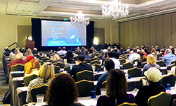 Image: The audience looks on as Susan Weinstein, MD, discusses imaging of ductal carcinoma in situ. Weinstein was one of several presenters during the multiday symposium, which drew world-renowned physicians and researchers to Amelia Island in February.