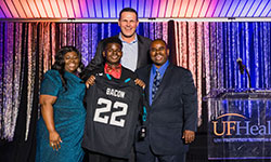 Image: Tina, Raqeem and Leonard Bacon at the 15th annual A Night for Heroes Gala. Tony Boselli, former Jacksonville Jaguars player, presented Raqeem with a custom jersey.